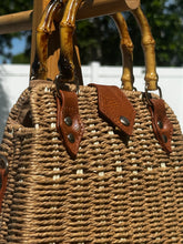 Bamboo Handle Woven Tote with brown leather accents and bamboo handles, perfect for beach outings and stylish adventures.