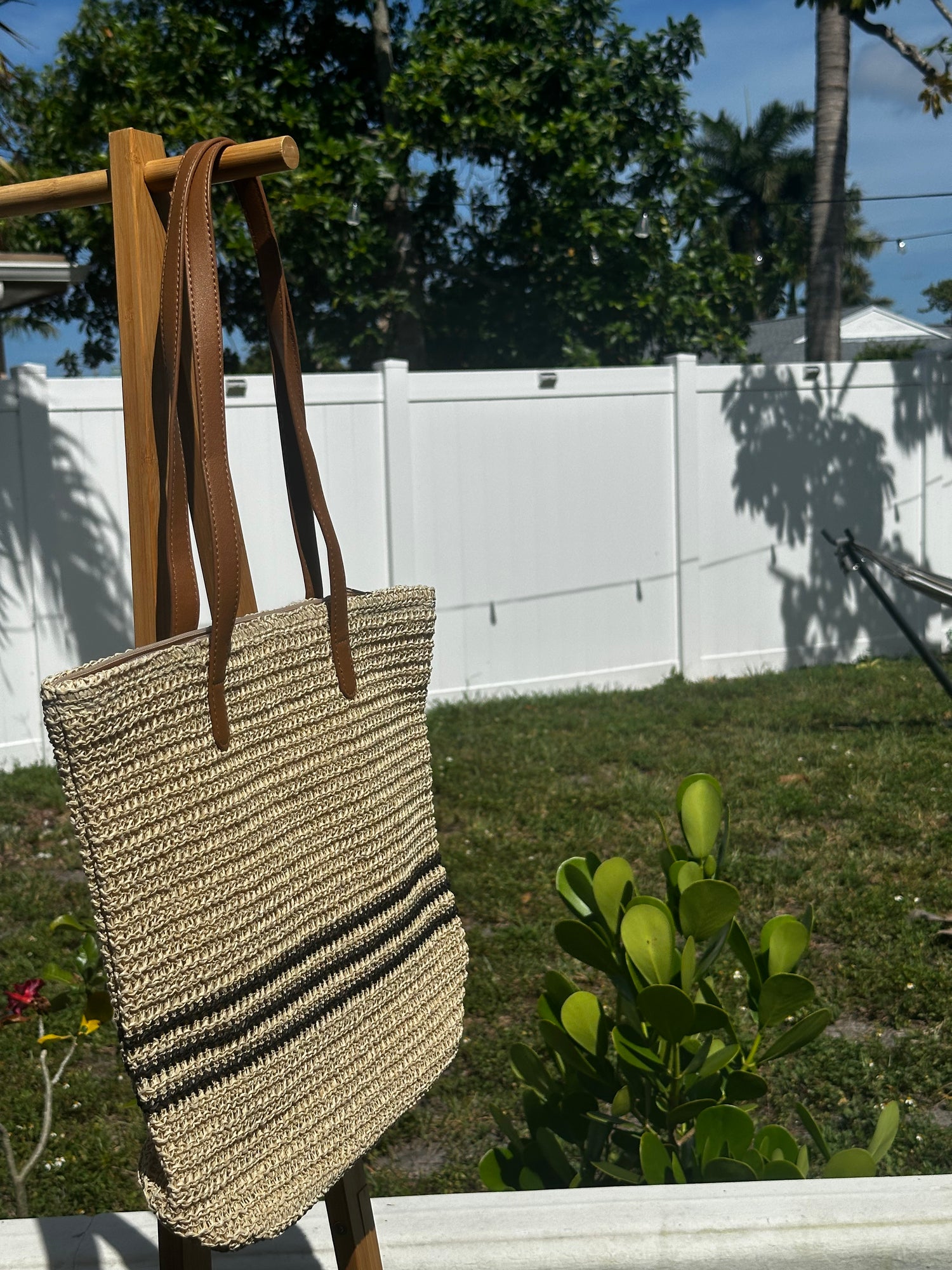 Coastal Stripe Woven Tote hanging outdoors, featuring a stylish design perfect for beach or everyday use.
